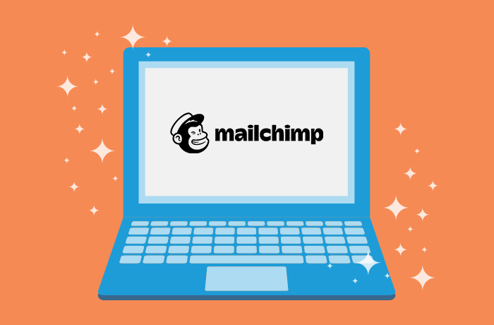 蓝笔记本电脑前方橙色背景图 屏幕上Mailchimp标识